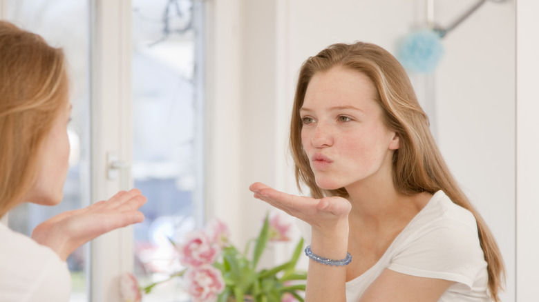 Woman blowing kiss to reflection