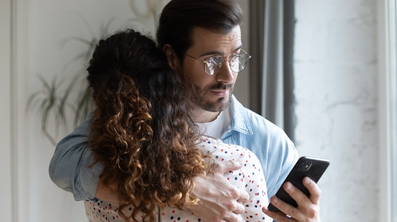 Distracted man hugging his partner