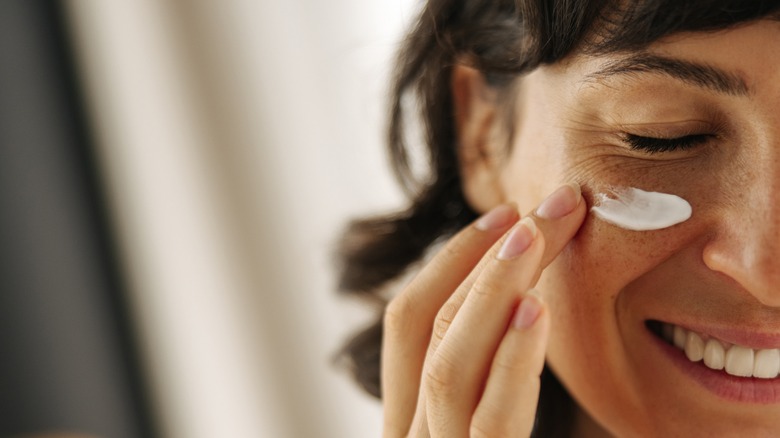 A woman applying moisturizer