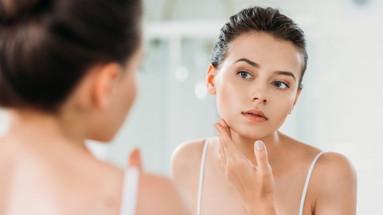 young woman looking at face in mirror