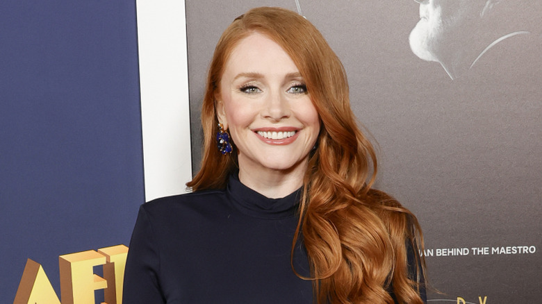 Bryce Dallas Howard with red hair smiling in a black top on red carpet