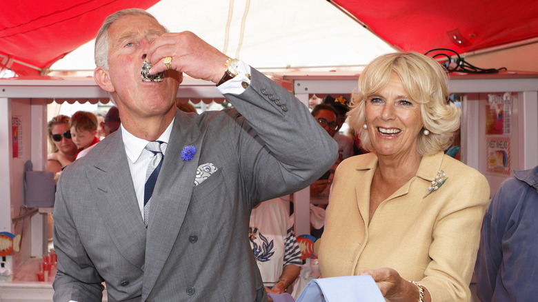 Prince Charles eating an oyster, Camilla holding napkin