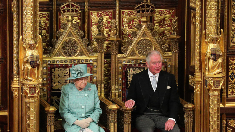 Queen Elizabeth II and Prince Charles sitting on thrones