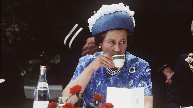 Queen Elizabeth II sips tea in Ireland wearing blue dress and hat