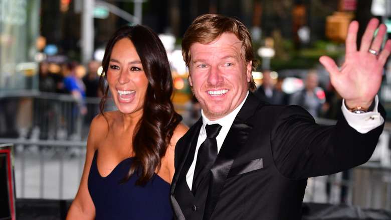 Chip and Joanna Gaines smiling and waving to cameras