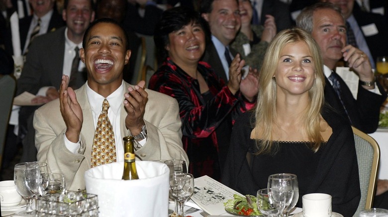 Tiger Woods sitting with Elin Nordegren smiling at an event