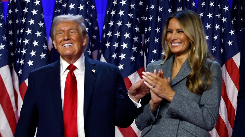 Donald Trump smiling and holding a hand out to Melania Trump