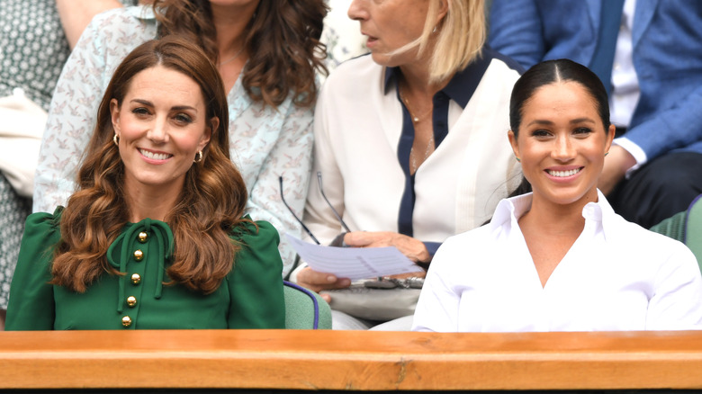 Kate Middleton and Meghan Markle smiling at an event