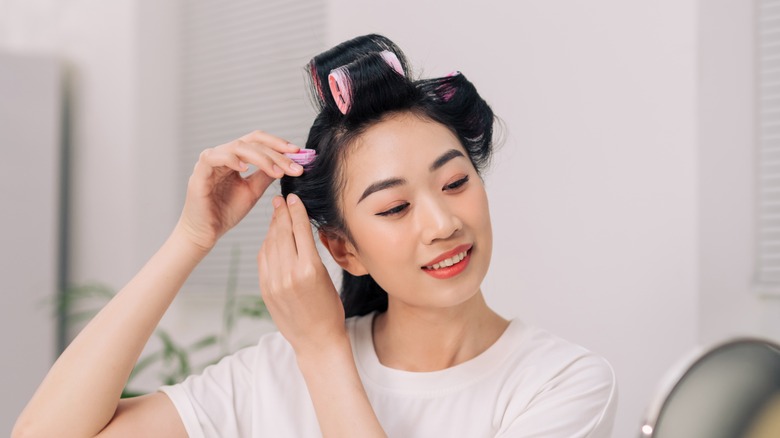 woman putting rollers in hair smiling