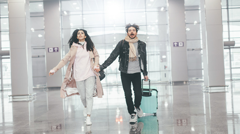 Couple running through the airport with a suitcase