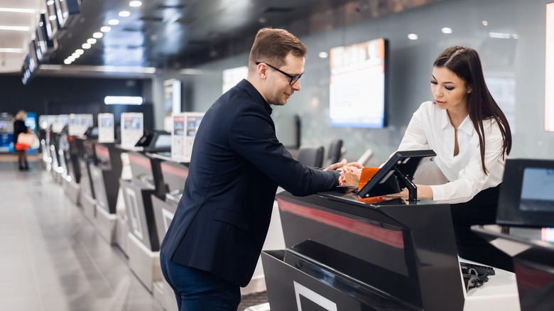 Airline employee helps a man check in for his flight