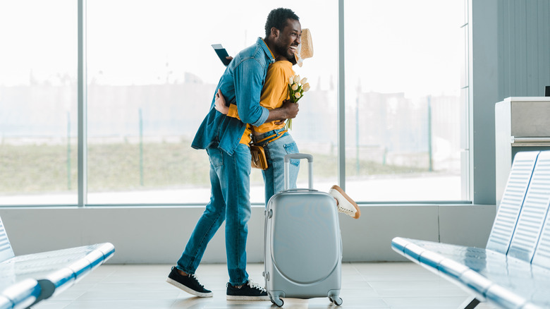 A man and a woman hug at the airport terminal