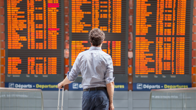 Man looking at the departures screen at the airport