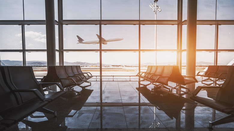 Airport with a plane flying outside the window