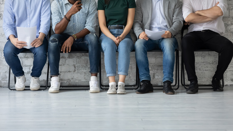 five people sit in a line of chairs 