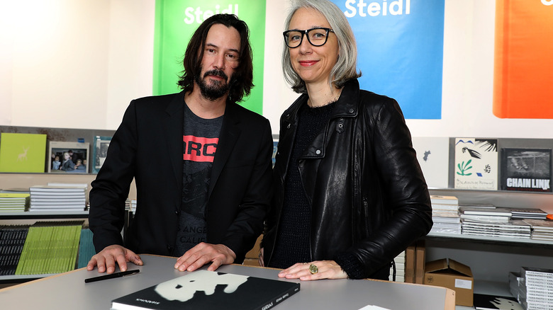 Keanu Reeves and Alexandra Grant pose by "Ode to Happiness" book