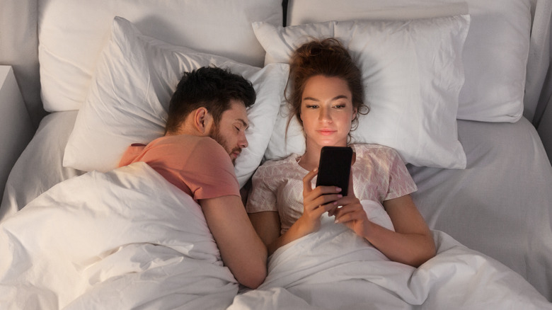 happy couple in bed with phone