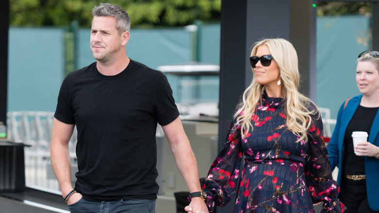 Ant Anstead in a black shirt with Christina Hall in a blue and red dress outside