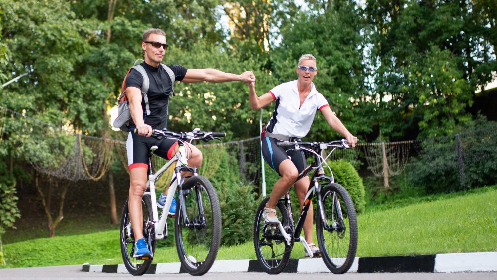 man and woman holding hands while biking