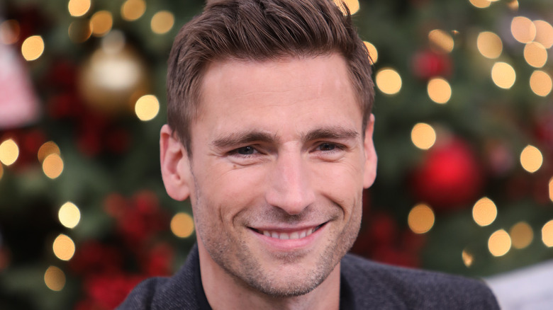 andrew walker smiling in front of blurred christmas tree