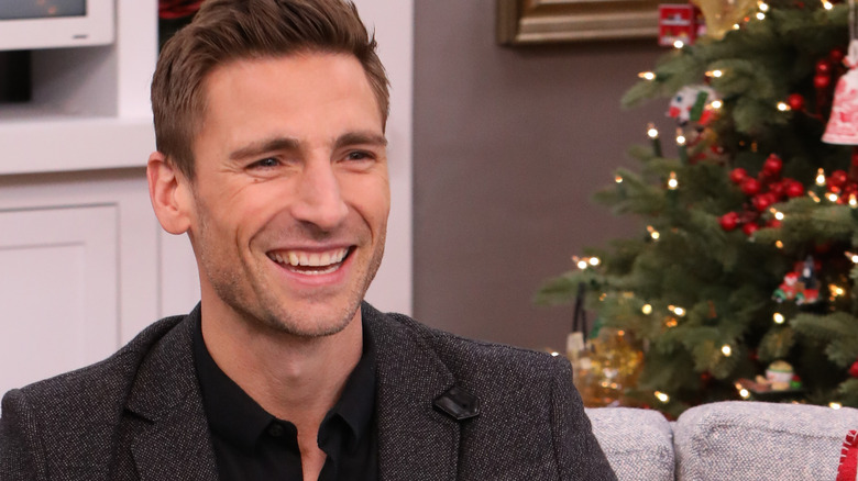 andrew walker laughing next to christmas tree