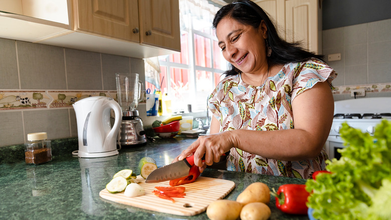 Woman smiles while cutting vegetables 