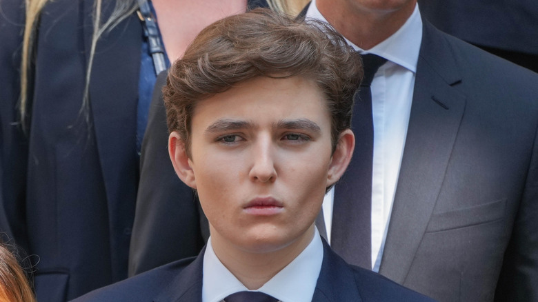 Barron Trump looking stern in a dark jacket