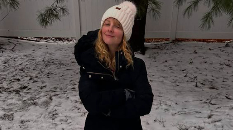 Melissa Rauch in a winter coat building a snowman outside in the snow