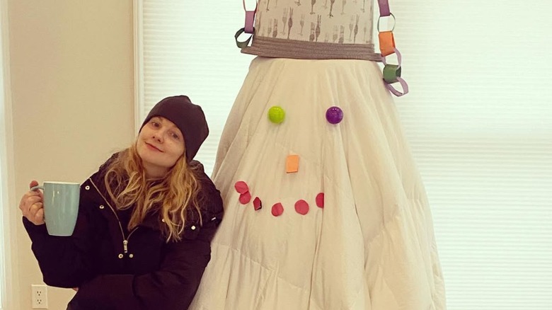 Melissa Rauch smiling with no makeup on next to a makeshift snowman