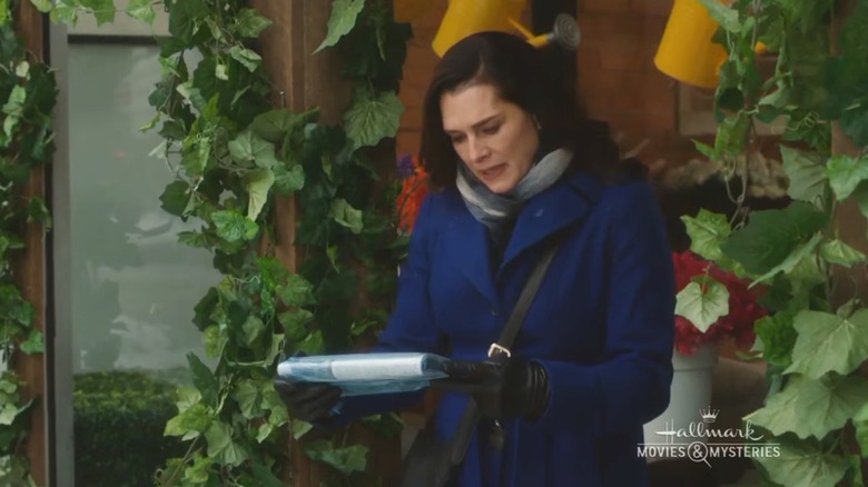 Brooke Shields looking at a newspaper in "Flower Shop Mystery: Snipped in the Bud"