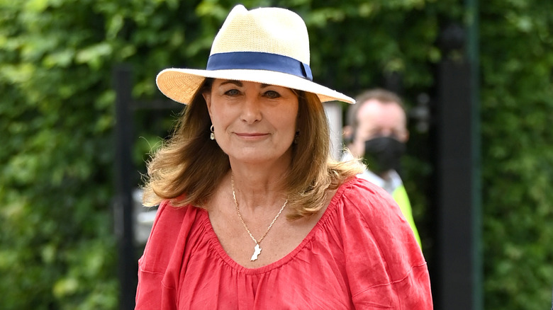 Carole Middleton walking outside in straw hat and red dress