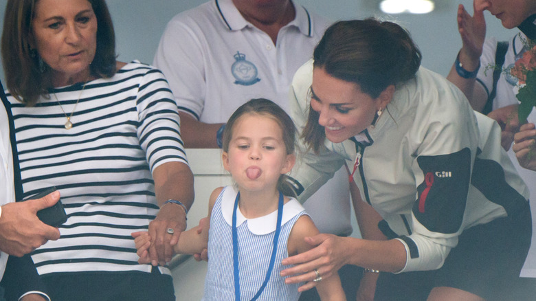 Carole Middleton and Princess Catherine pull Princess Charlotte back as she sticks out her tongue