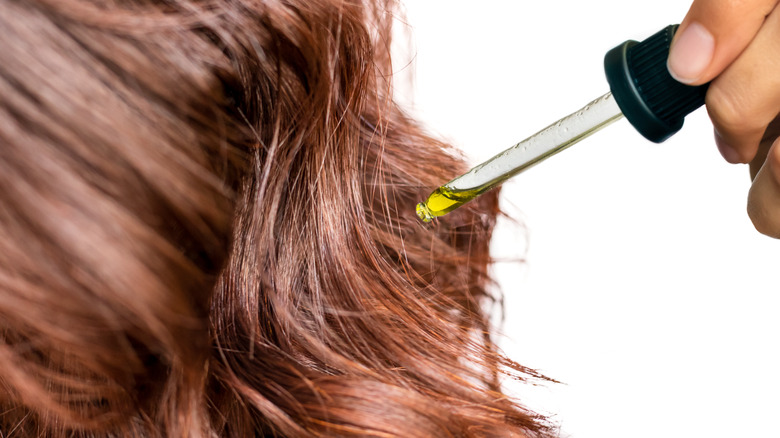 Woman applying oil to hair