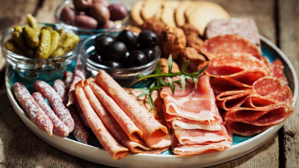 A charcuterie board with meats and vegetables