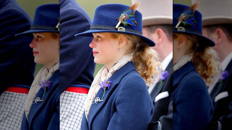 Lady Louise side profile in blue coat and hat