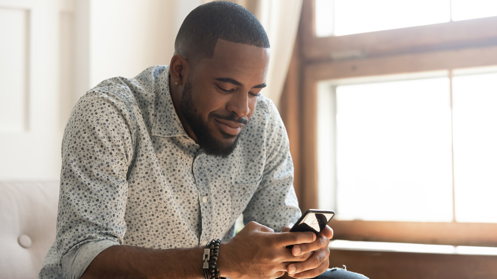 Young male sitting and looking through his phone 