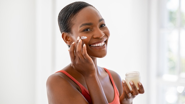 Woman smiling while applying face cream