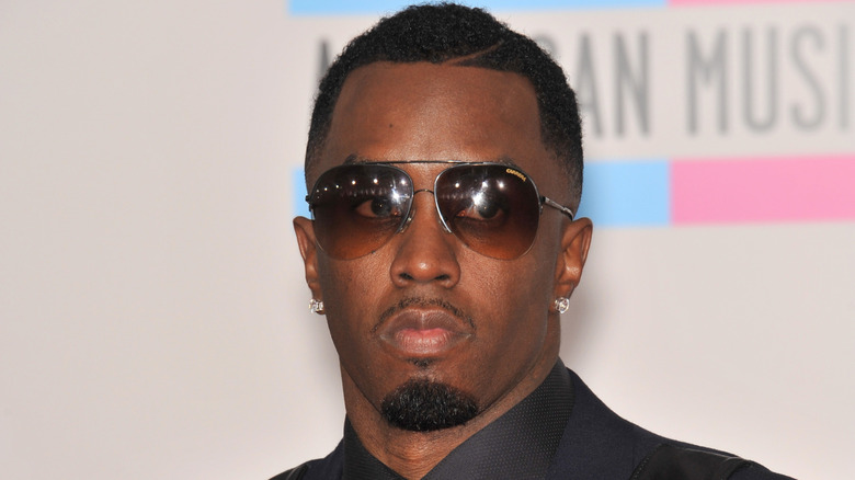 Sean "Diddy" Combs stares while wearing sunglasses and bold earrings