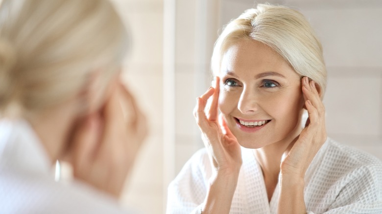 Elderly woman touching face in mirror