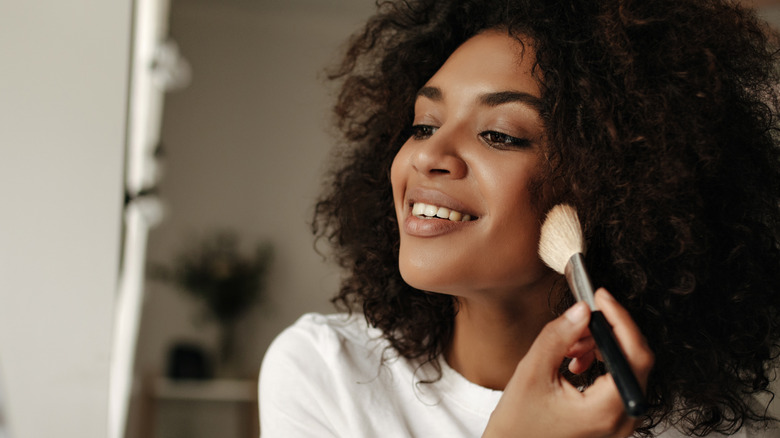 Woman smiling using makeup brush