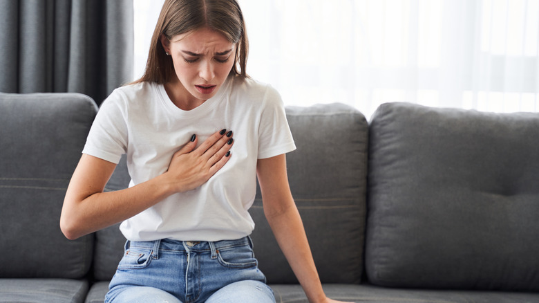 Woman sitting on couch with chest pain 