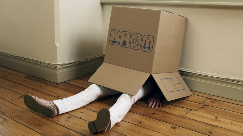 Person sitting on floor with box on their head