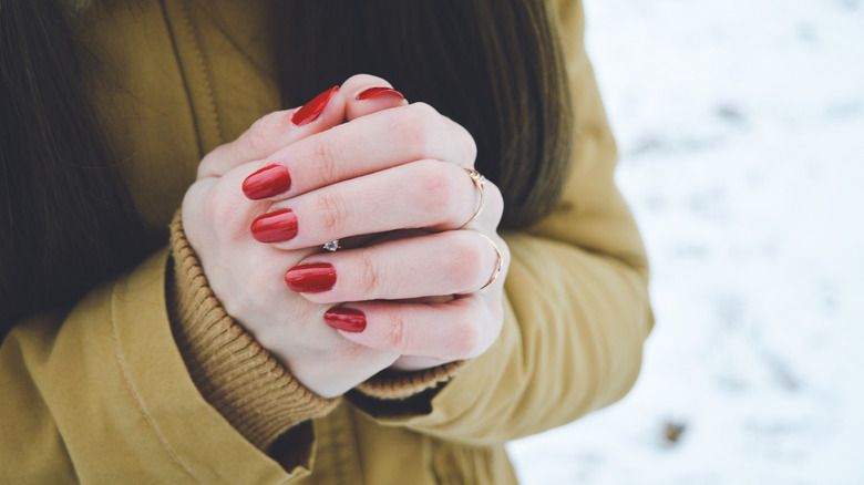 woman clasping cold hands outdoors