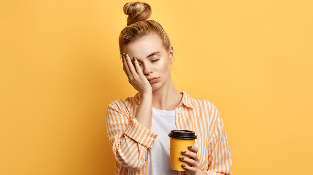 Tired woman holding coffee cup