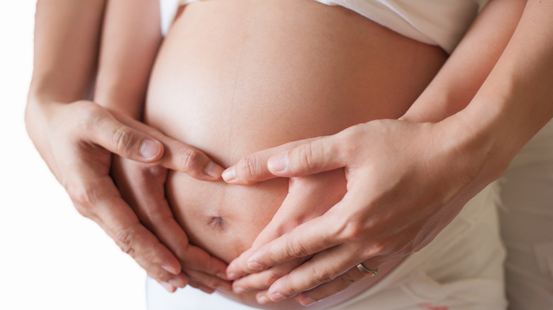 Couple holding pregnant belly