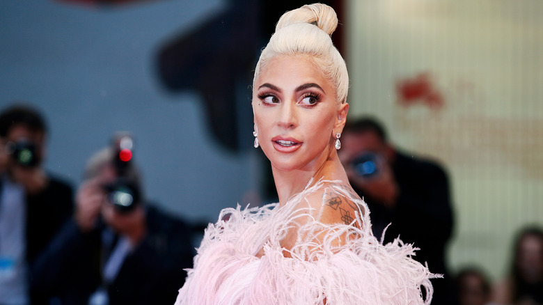 Lady Gaga posing on red carpet with blonde bun