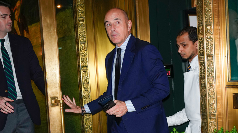 Matt Lauer stares to the side whilst walking through a door in blue tuxedo