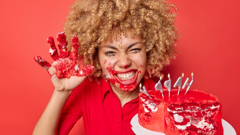 Woman with cake messy hand and mouth