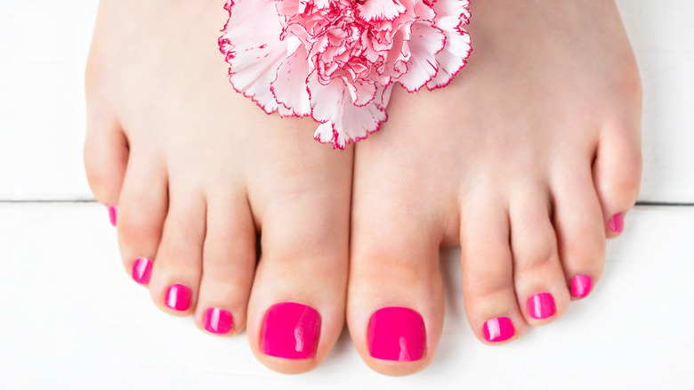 Toes with hot pink nail polish and a flower