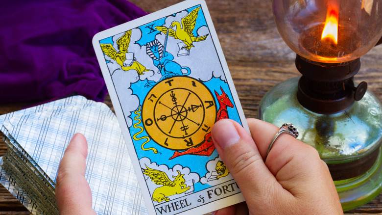 Hand holding Wheel of Fortune tarot card